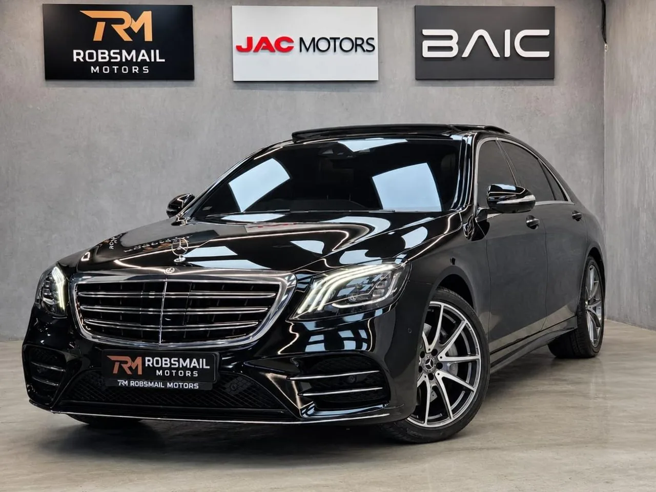A Mercedes-Benz S-Class in the Robsmail Bryanston showroom, in front of the Robsmail, JAC and BAIC signs